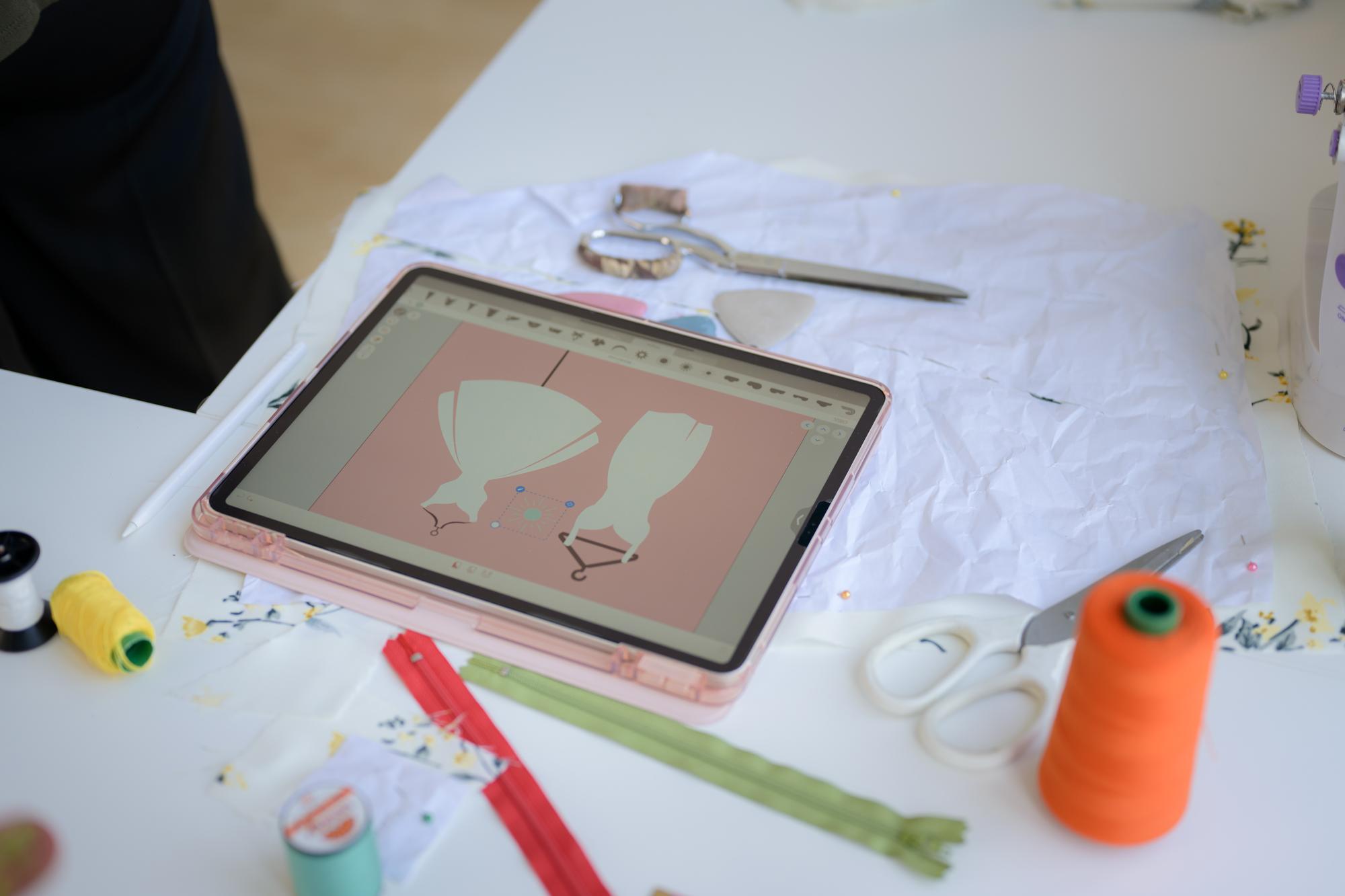 Studio workbench with threads and digitized pattern on tablet